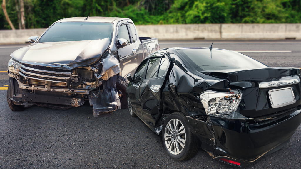 Can I Sue Someone After a Car Accident in Arizona? – Valley Injury Team Two damaged vehicles after a head-to-head crash on a road: a silver pickup with a crushed front end and a black sedan with extensive rear damage on the right. – Can I Sue Someone After a Car Accident in Arizona? – Valley Injury Team